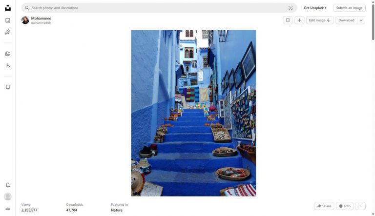 Blue painted stairs and walls of Chefchaouen medina Morocco lined with traditional crafts and colourful textiles