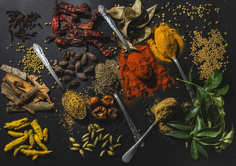 Indian spices flatlay including ginger, garlic, turmeric, chillies and coriander - ingredients for Bengali maachher jhol fish curry
