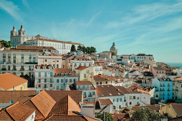 Aerial view of Lisbon Alfama district with terracotta rooftops, the Tagus estuary and blue sky